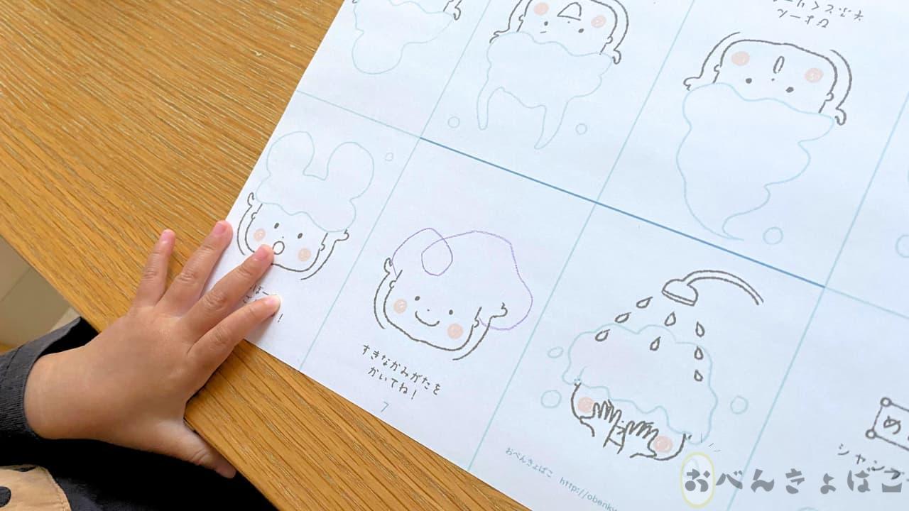 メニュー表にかみがたを描いている子どもの手