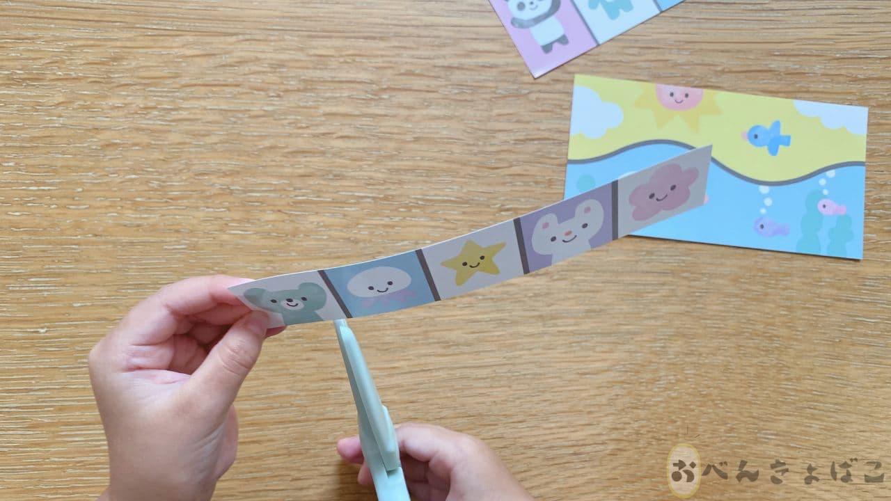 子どもがはさみで紙を切っている画像